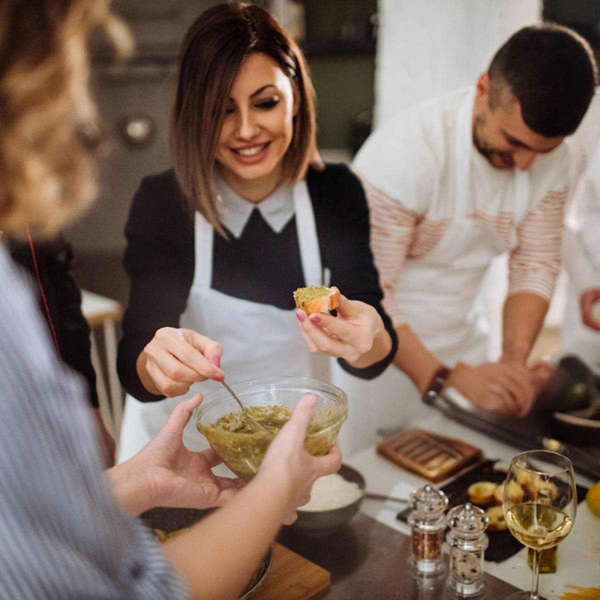 Photo of a young woman in a kitchen during a cooking class, preparing bruschetta